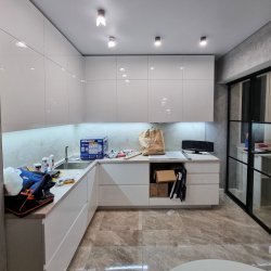 Белая глянцевая кухня без ручек и раздвижная перегородка на балкон